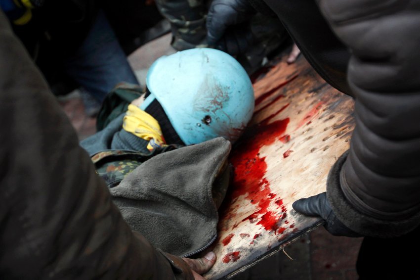 Anti-government protesters carry an injured man on a stretcher after violence erupted in the Independence Square in Kiev